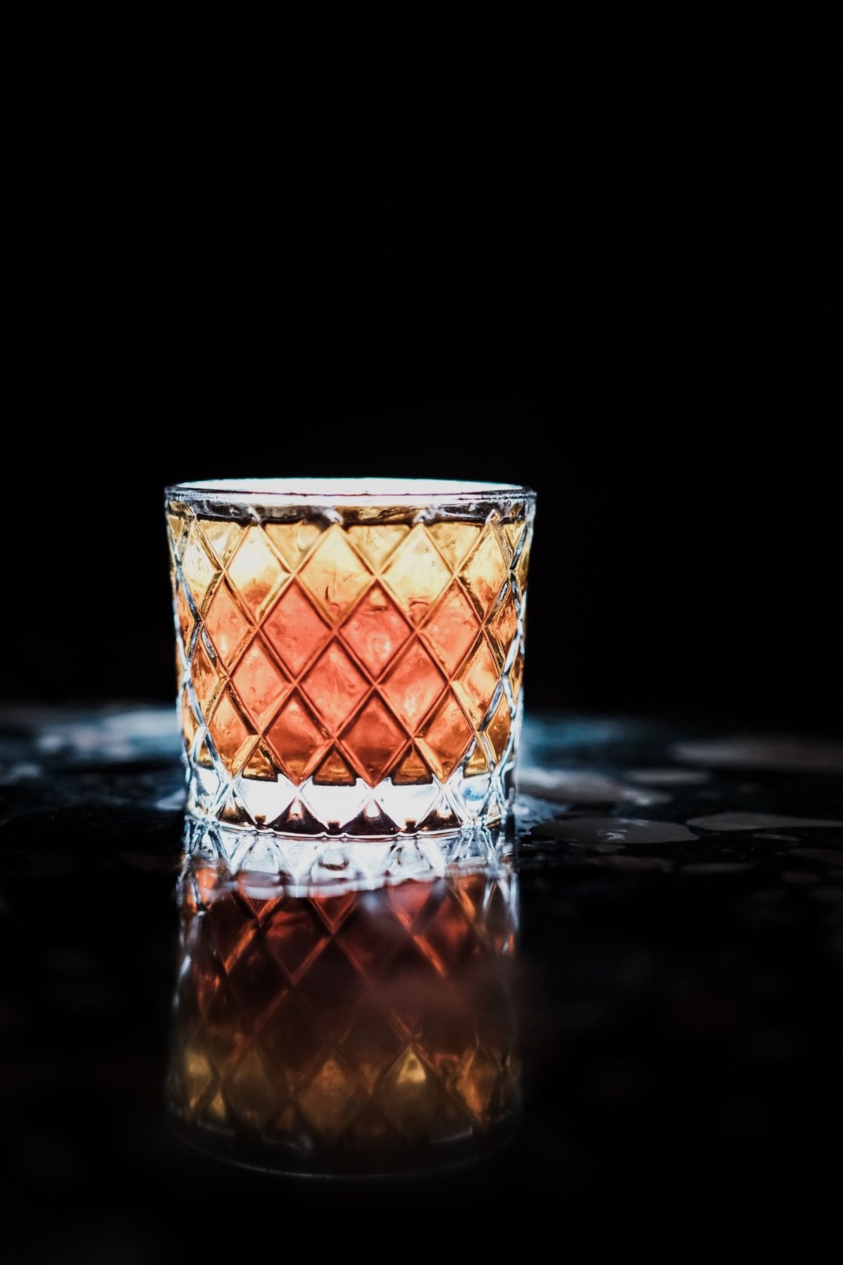 A cut-crystal tumbler on a black surface.